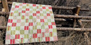 Gift Swap Christmas quilt haning on log-rail fence in nature